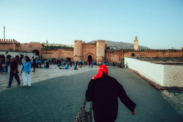 People walk in front of a moroccan city gate.